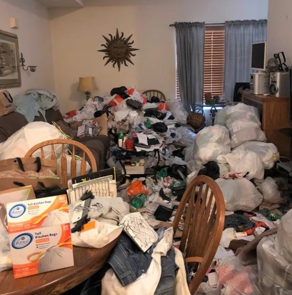 Living room before — floor-to-ceiling bags and clutter filling the entire room
