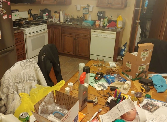 Kitchen before cleaning — cluttered counters and table covered in items