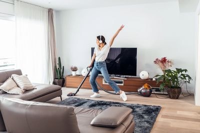 Woman dancing while vacuuming a clean living room
