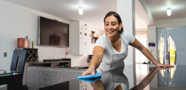 Cleaner wiping down a kitchen countertop with a blue cloth