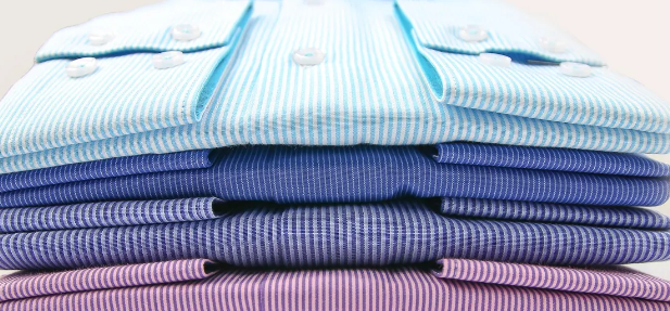 Neatly pressed and folded dress shirts in multiple colors